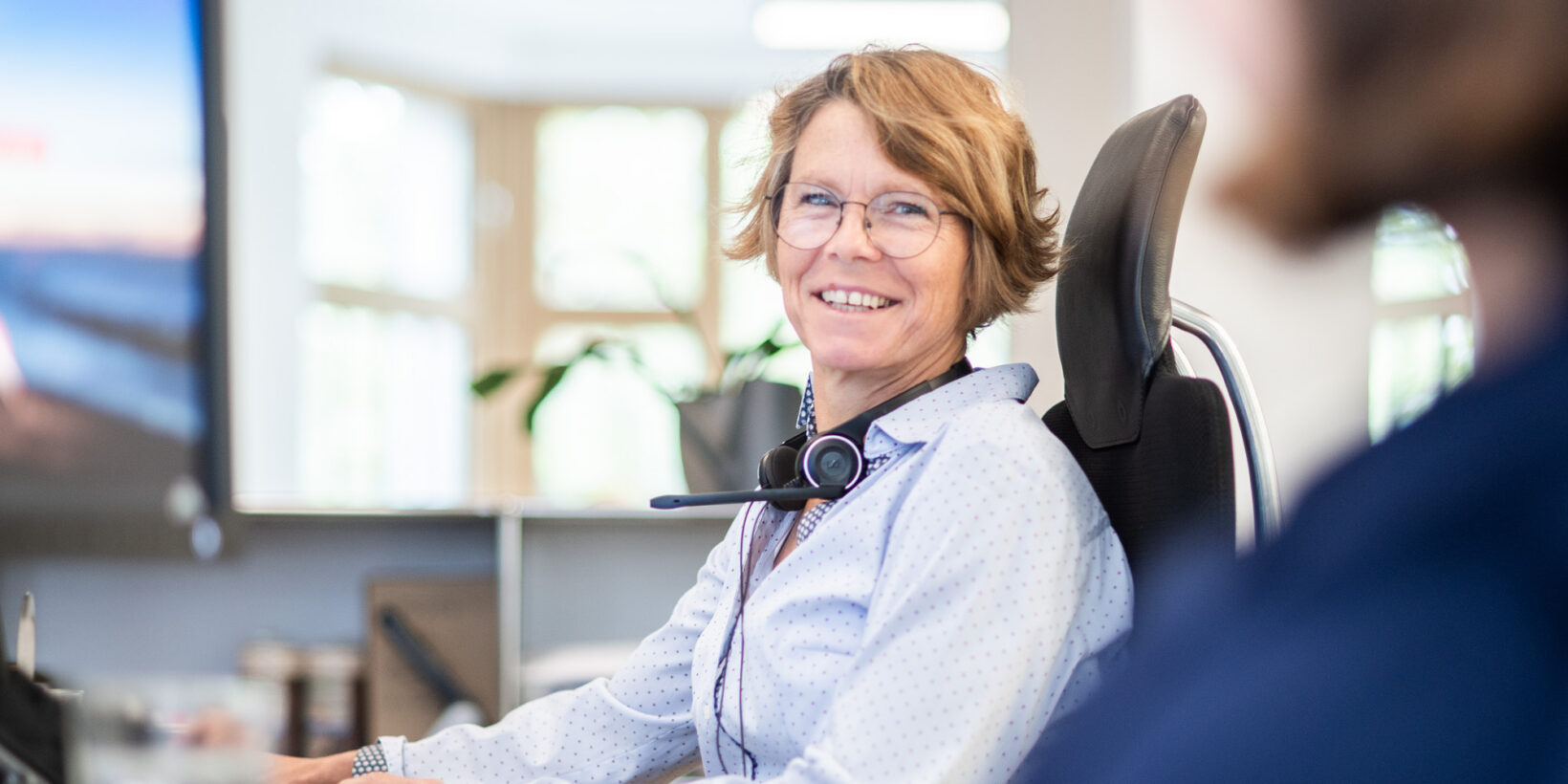 BMP-Mitarbeiterin mit Headset lächelt am Arbeitsplatz im Berliner Büro.