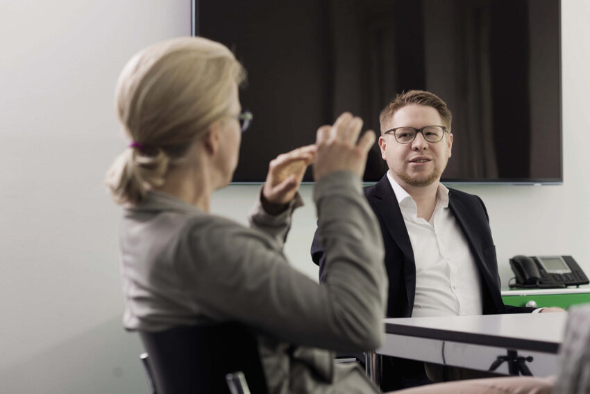 Besprechung bei BMP Projektmanagement mit zwei Mitarbeitenden im Austausch während eines Meetings.