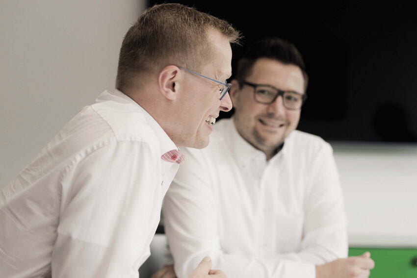 Zwei Mitarbeitende von BMP Projektmanagement im persönlichen Austausch während eines Meetings.