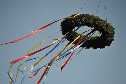 Richtkranz mit bunten Bändern bei einem Richtfest eines Bauprojekts vor blauem Himmel.