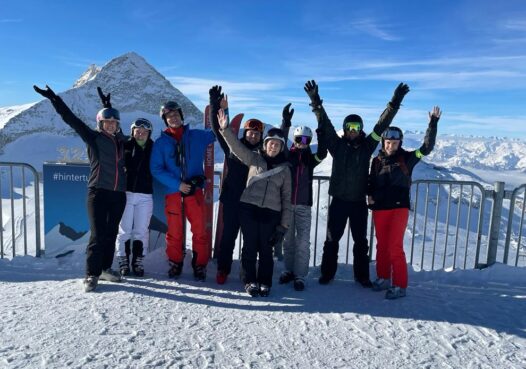 BMP Mitarbeitende bei einem gemeinsamen Ski-Teamevent auf einem verschneiten Berggipfel.