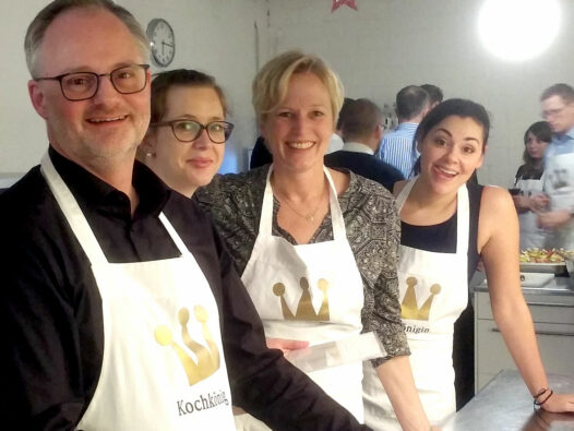 BMP Mitarbeitende bei einem gemeinsamen Koch-Event in einer Küche mit Kochschürzen und guter Stimmung.