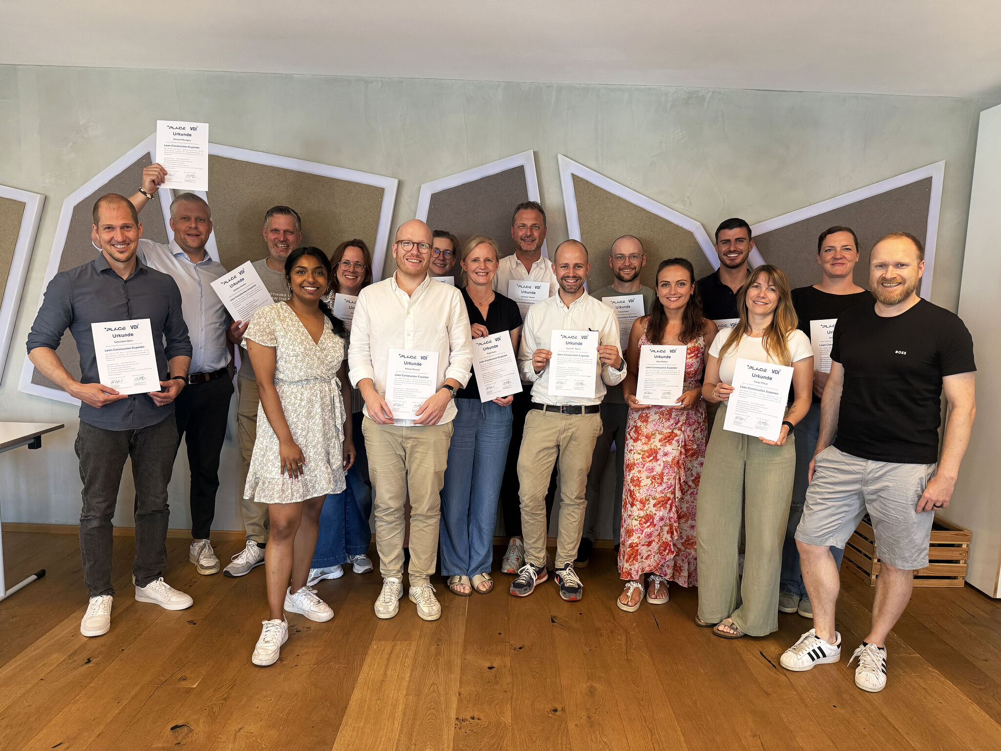 Gruppenfoto der Teilnehmenden nach erfolgreichem Abschluss der VDI 2553 Lean Construction Experten-Zertifizierung bei der BMP, mehrere Personen halten ihre Urkunden in die Kamera.