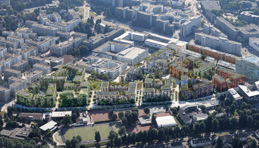 Luftaufnahme eines des Quartiers D.STRICT mit modernen Wohn- und Bürogebäuden mit begrünten Dächern, umgeben von Straßen, Parks und Sportanlagen.