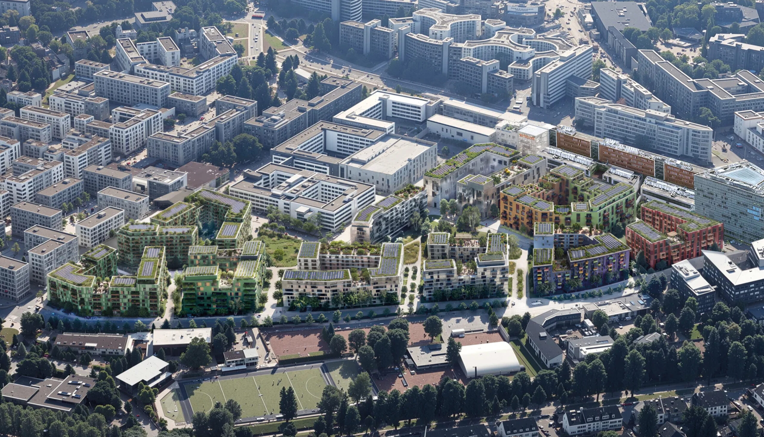 Luftaufnahme eines des Quartiers D.STRICT mit modernen Wohn- und Bürogebäuden mit begrünten Dächern, umgeben von Straßen, Parks und Sportanlagen.
