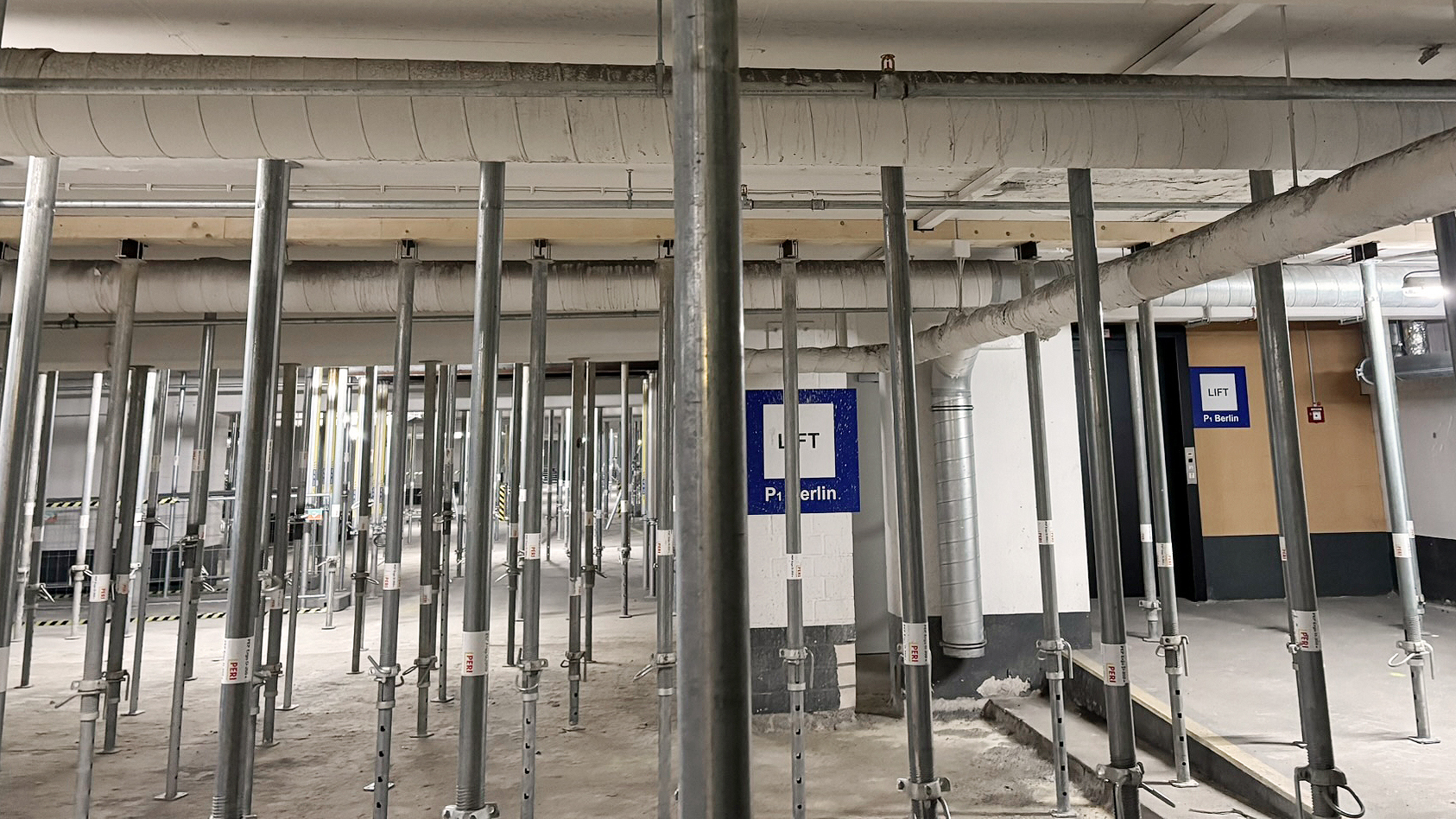 Parkhaus Innenansicht mit temporär eingebauten Stützen, welche die Zwischendecke in ihrer horizontalen Lage stabilisieren.