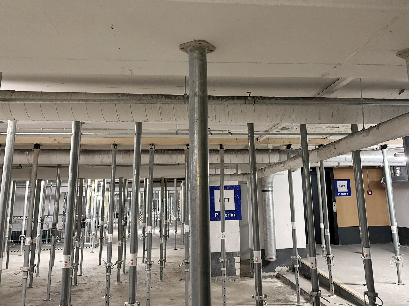 Parkhaus Innenansicht mit temporär eingebauten Stützen, welche die Zwischendecke in ihrer horizontalen Lage stabilisieren.