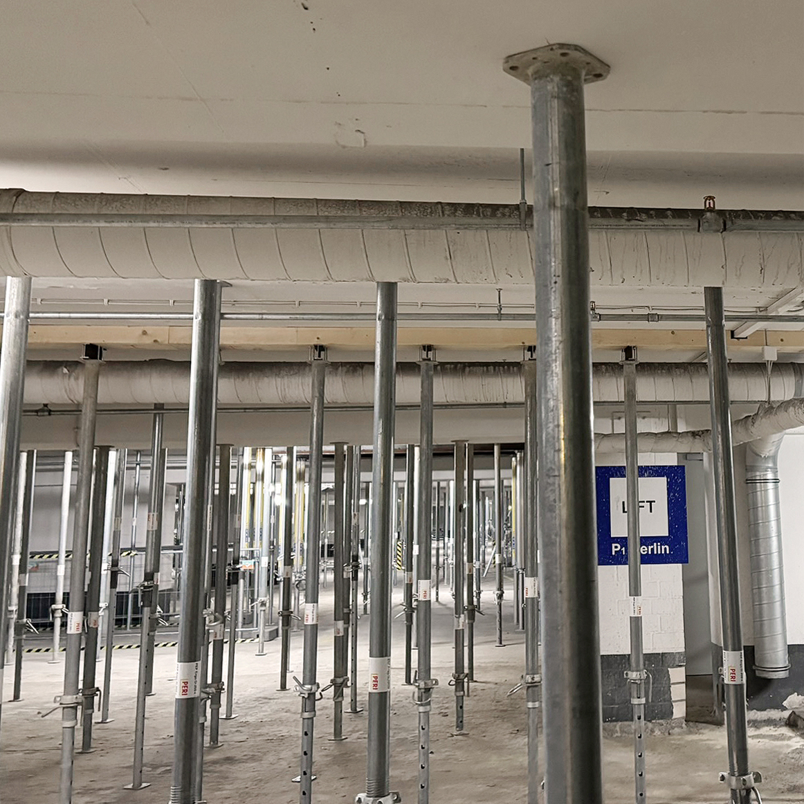 Parkhaus Innenansicht mit temporär eingebauten Stützen, welche die Zwischendecke in ihrer horizontalen Lage stabilisieren.