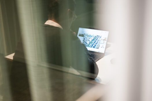 BMP Mitarbeiter prüft am Laptop eine Immobilienplanung mit Lageplan und Gebäudedaten.